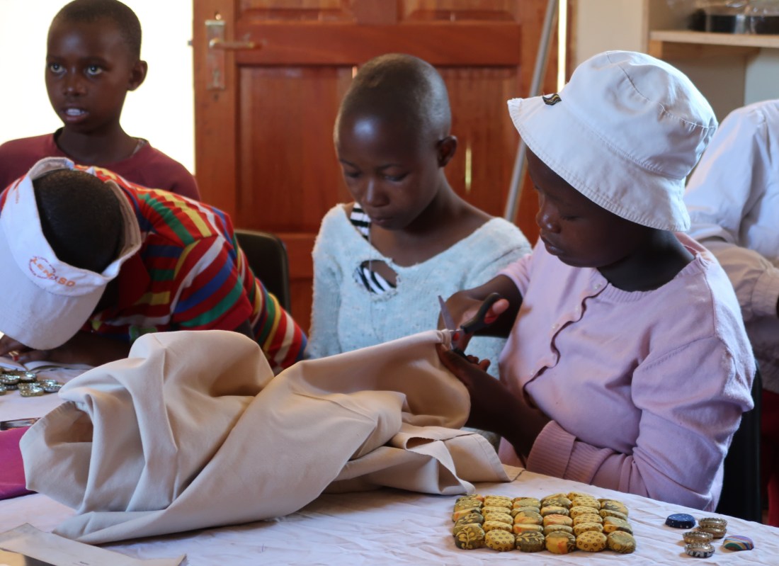 a young girl focuses on cutting fabric in a young women's sewing group run by the Malealea Development Trust and Africa's Gift