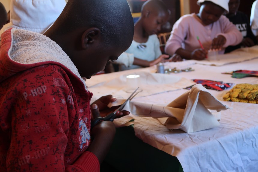 a young girl in Malealea cuts fabric in the Malealea Development Trust's Young Women's Support Group in partnership with Africa's Gift