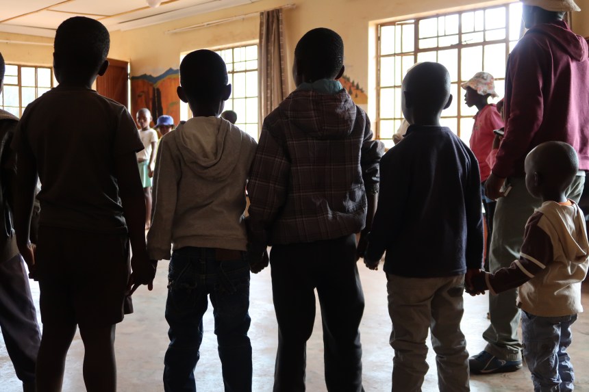 the silhouettes of five small boys holding each other's hands during the Malealea Development Trust's Children's Day in Lesotho, Southern Africa