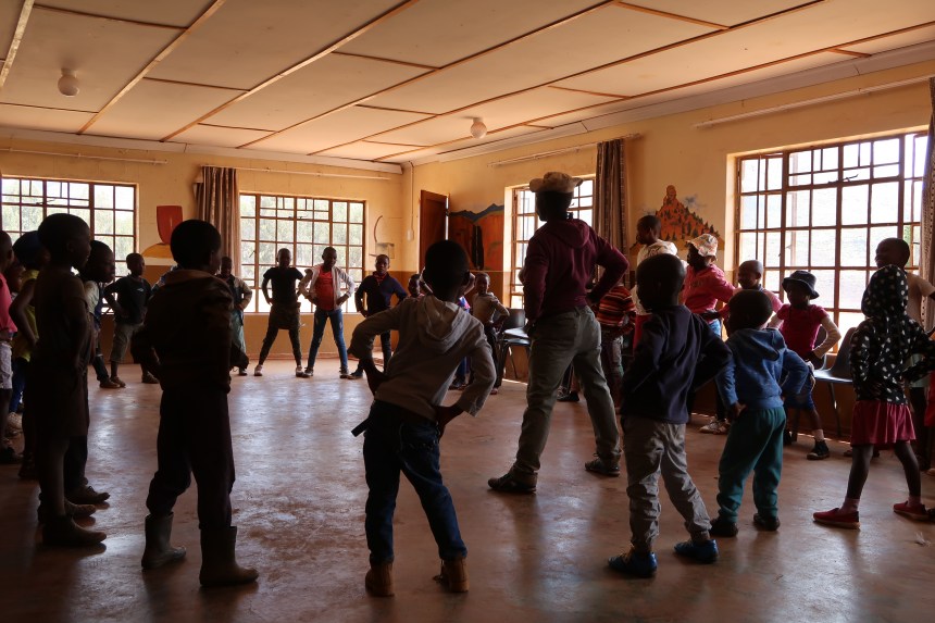 children follow the MDT Field Worker's lead through stretching exercises at the community hall in Lesotho, Southern Africa