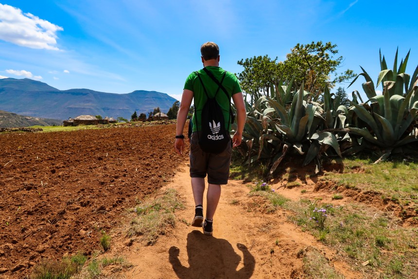 a man walks by a plot of land and some wild aloe plants in the village of Malealea, Lesotho, Southern Africa, photo by Kelly Benning