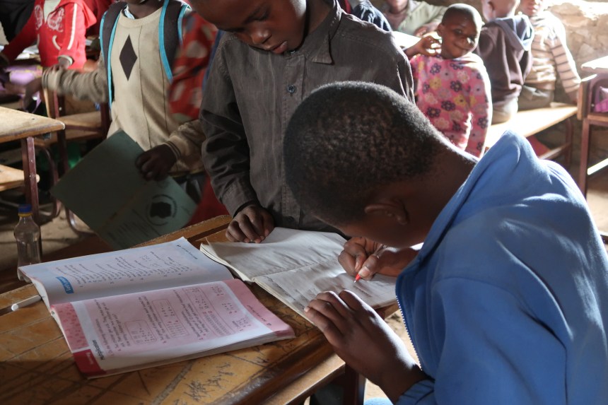 a young student writes in the notebook of another student at school