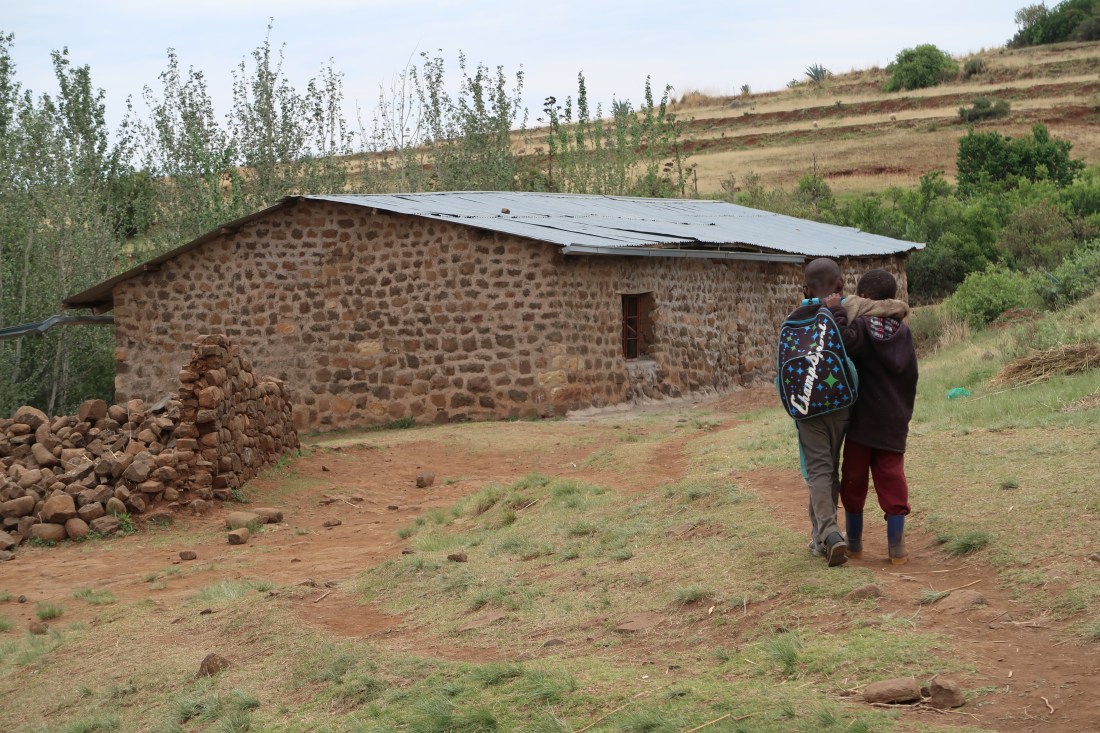 two young boys walk arm-in-arm to their small school in Malealea, Lesotho, the Molai Primary School